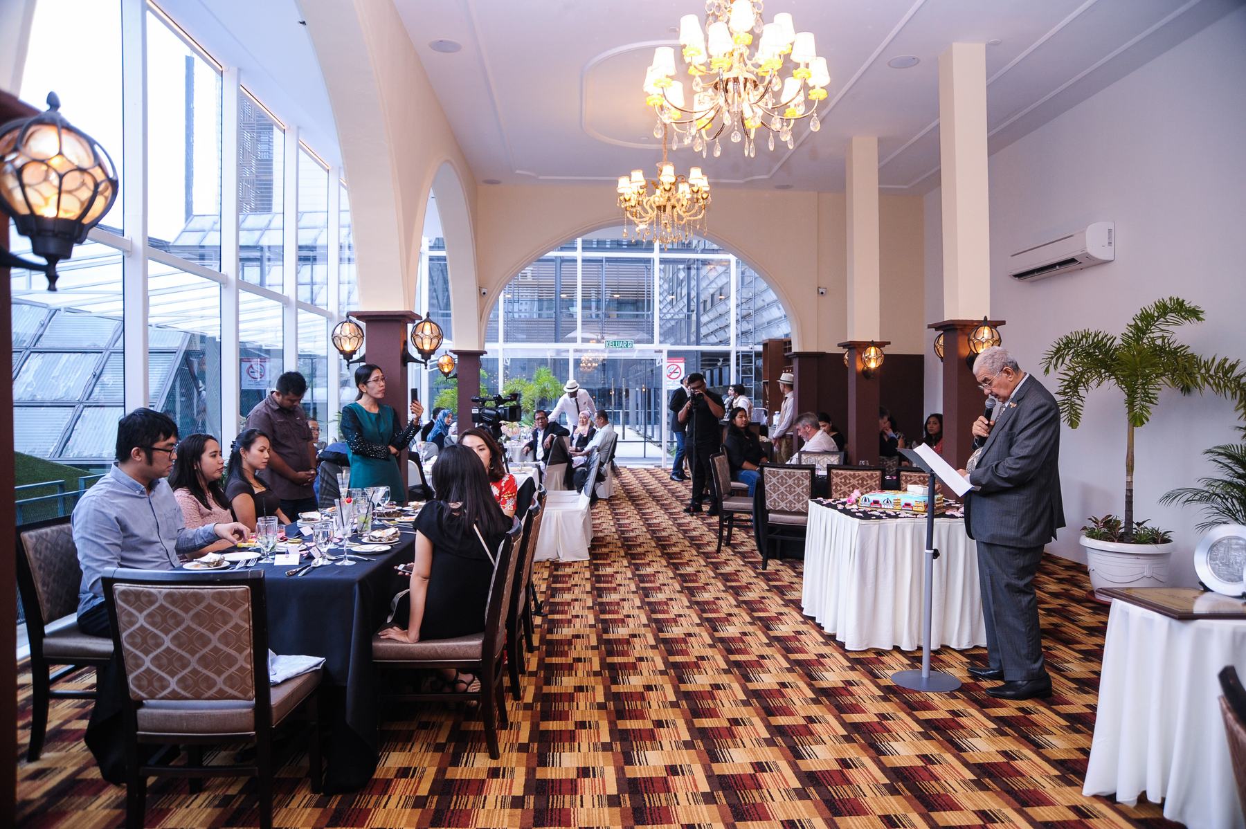 Guests dining in the arched hall under chandeliers